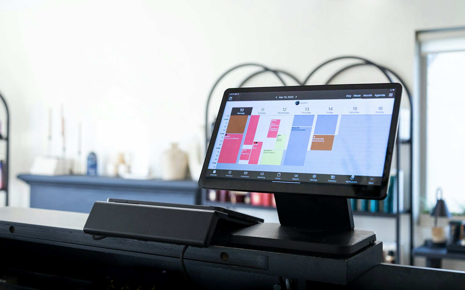 A digital display showing appointments and the day's schedule at a salon front desk