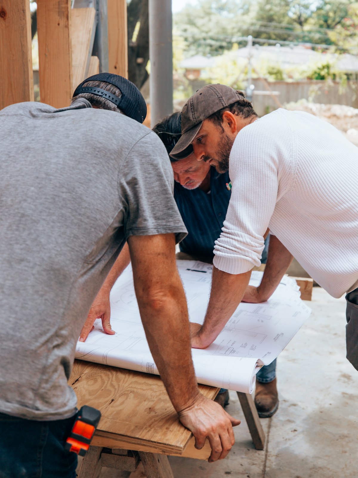 A small construction crew leaning over a set of plans at a job site