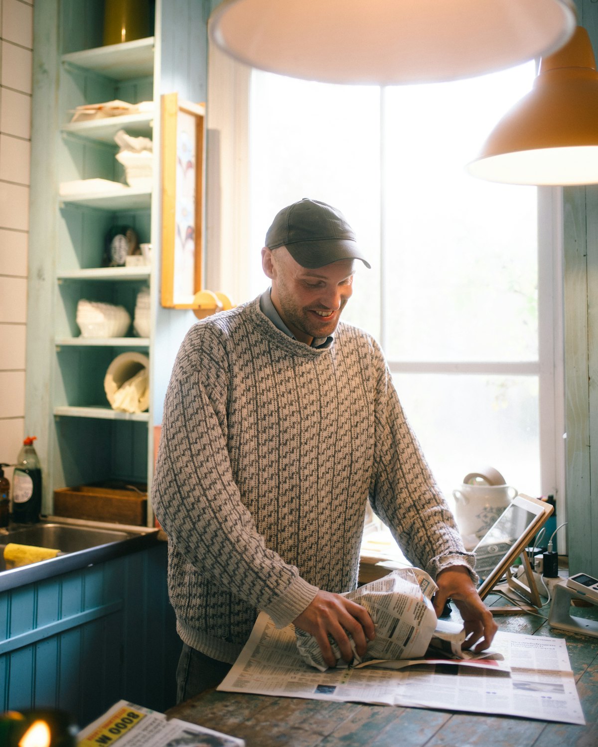 A shopkeeper wrapping an item in newspaper at a wooden counter