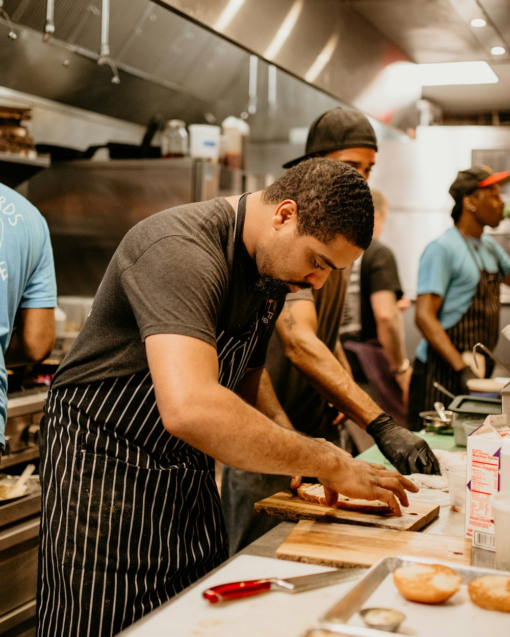 Cooks in aprons preparing food at a cutting board in a busy restaurant kitchen