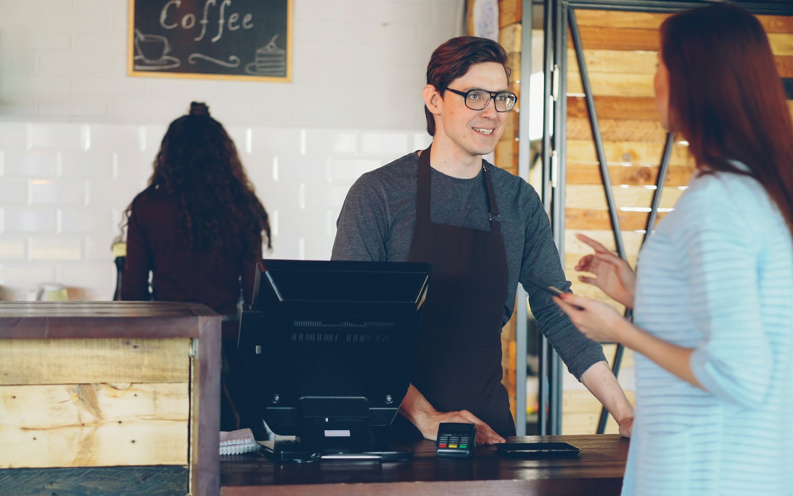 A barista chatting with a customer at a coffee shop counter