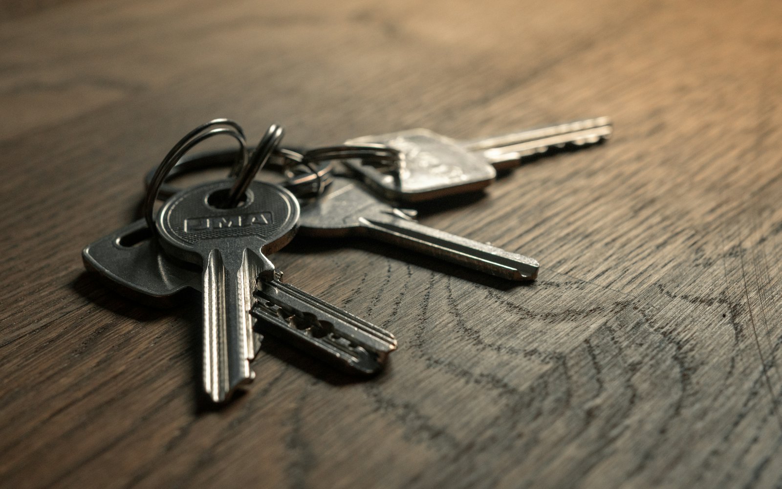 A ring of house keys lying on a dark wooden table