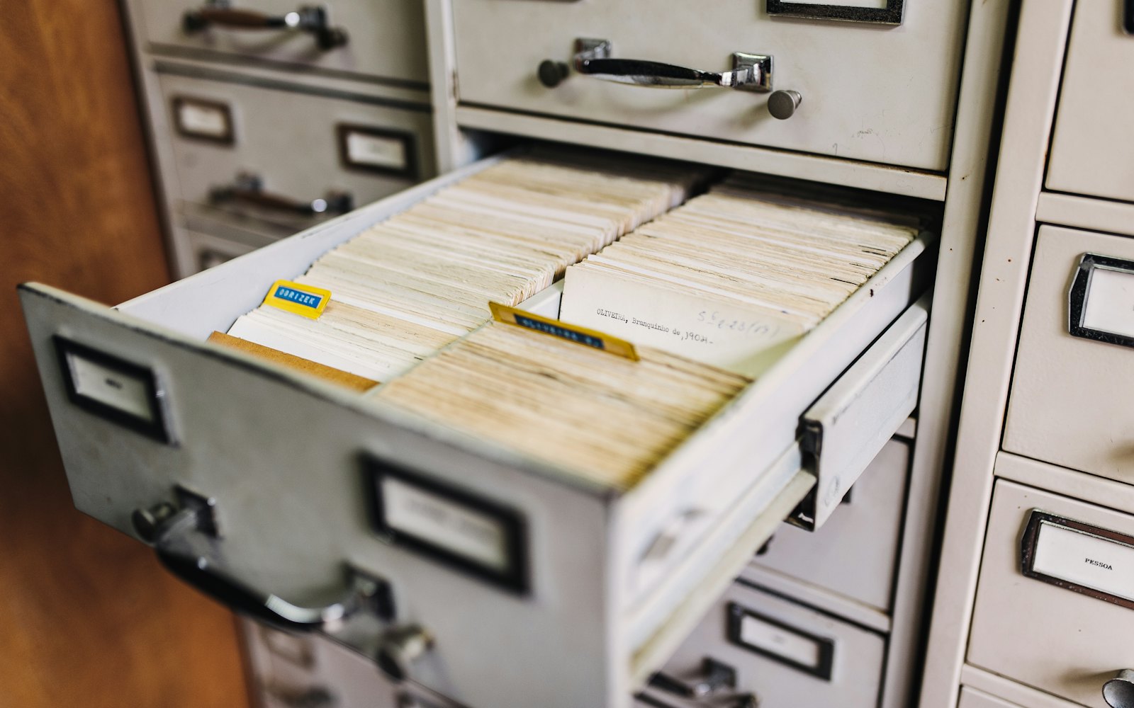 An open metal filing cabinet drawer packed with index cards