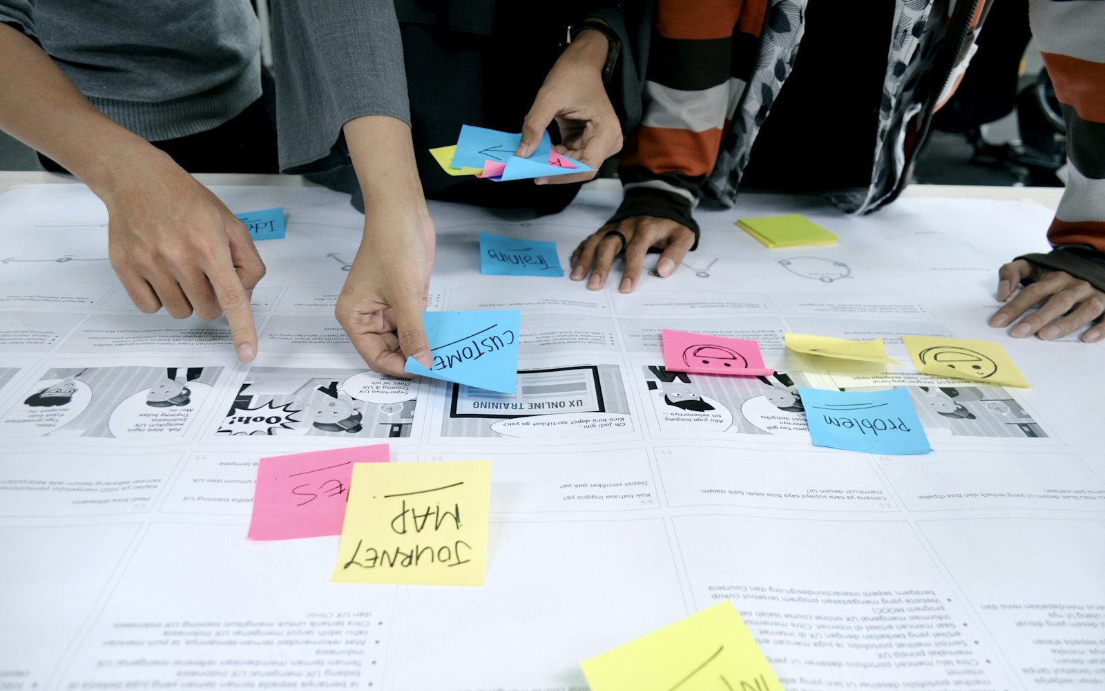 Hands arranging colorful sticky notes on a large sheet of paper during a planning session