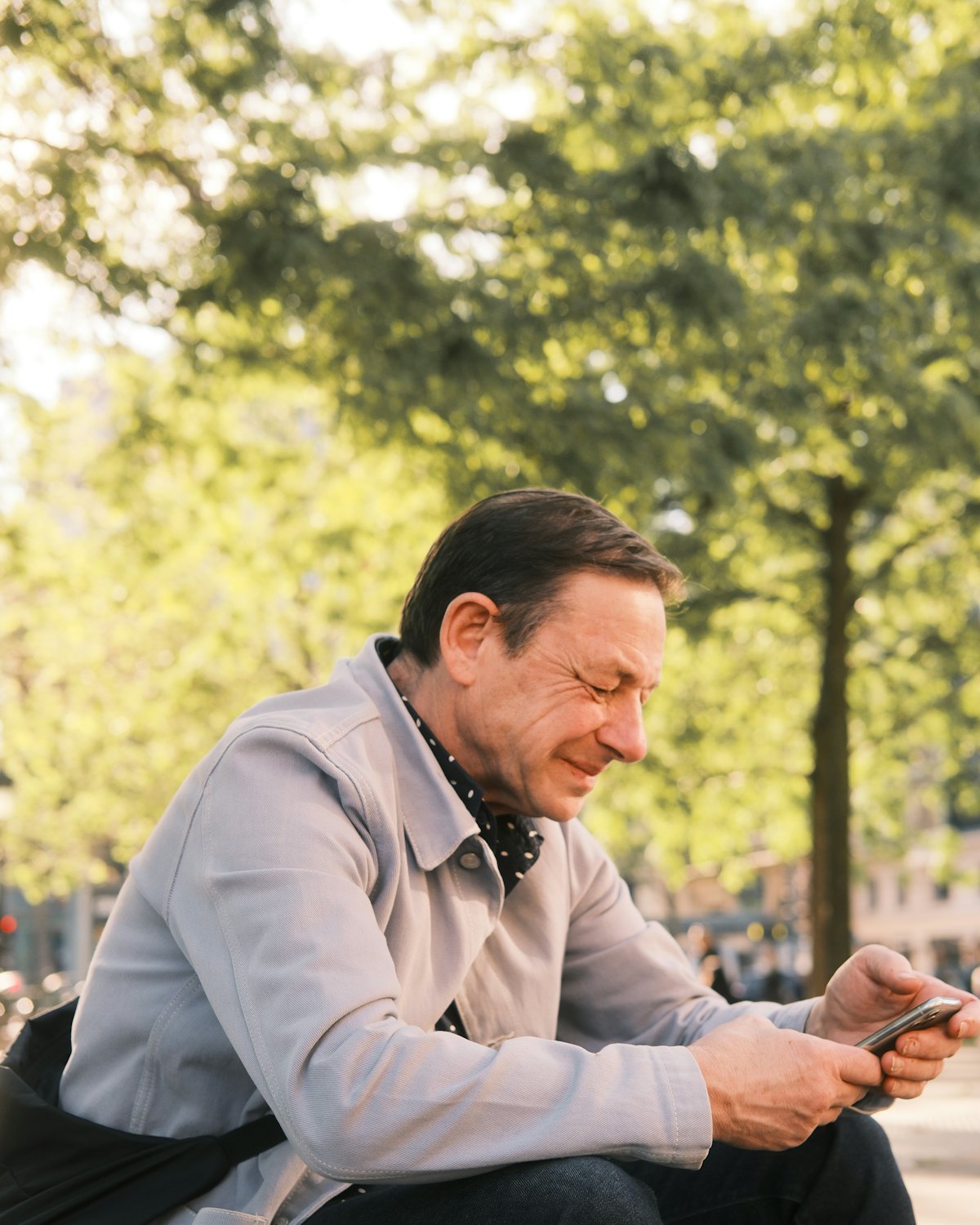 A man sitting outdoors reading his phone