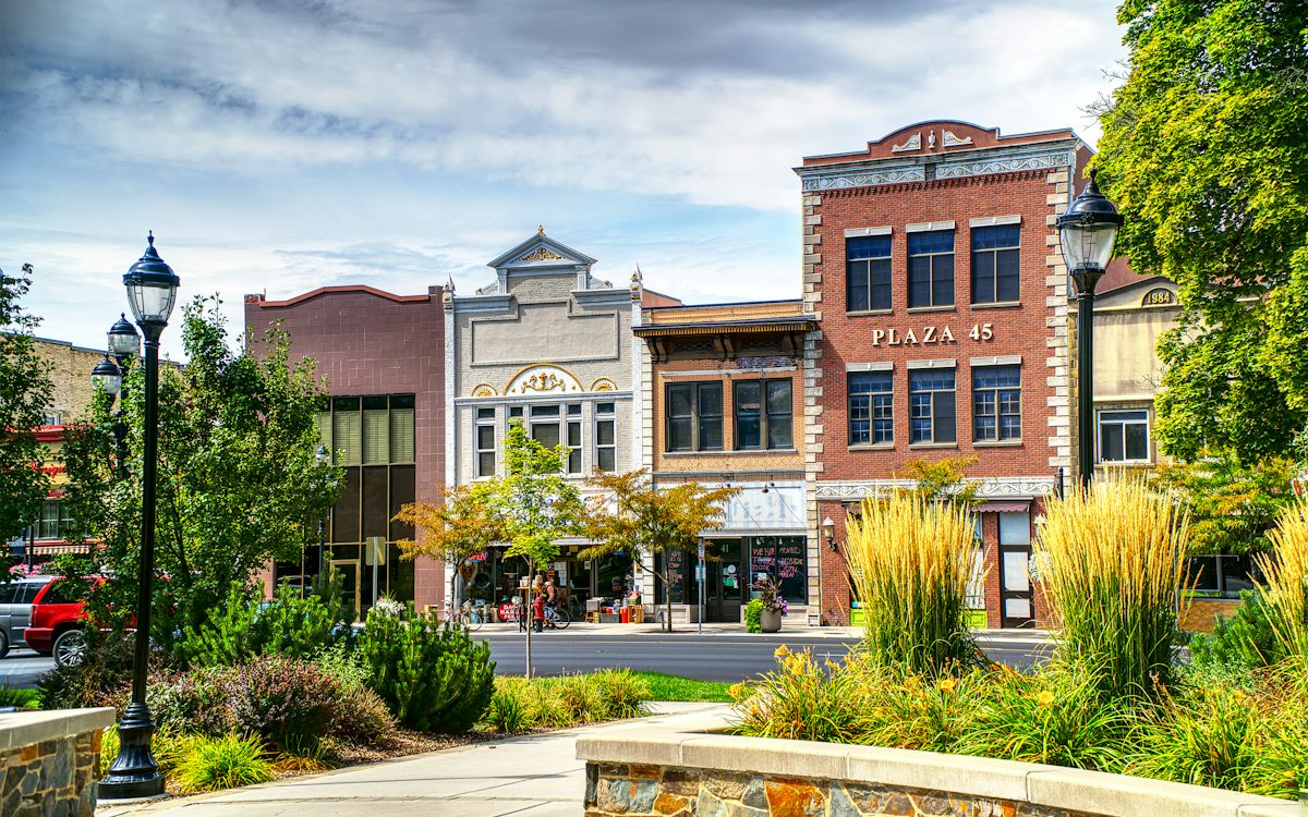 Brick storefronts on a small-town main street seen across a landscaped plaza